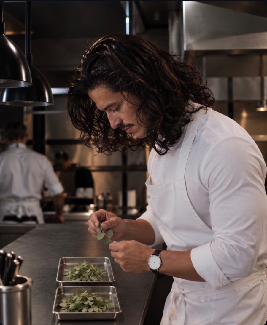 Greg at the pass, picking leaves from a sprig of herbs